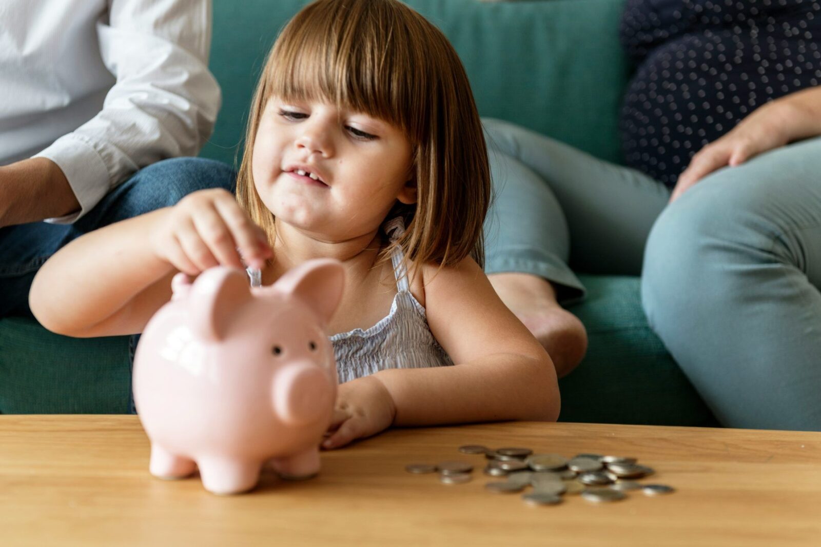 A child putting coins into a piggy bank, saving like a Junior ISA